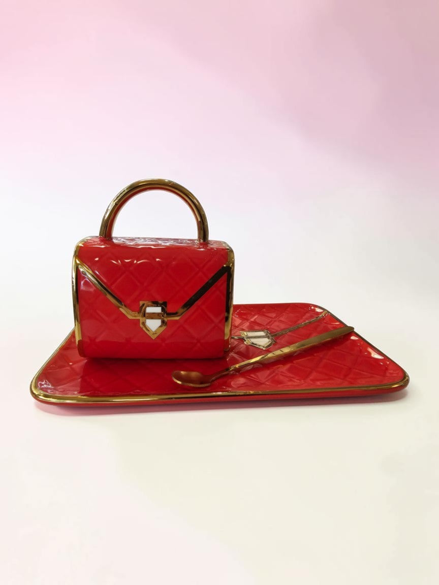 Set de taza y bandeja Libreria Wow de cerámica roja con diseño de bolso acolchado y detalles en dorado brillante.
