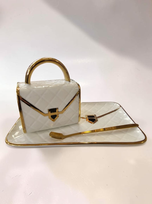 Set de taza y plato Libreria Wow de cerámica blanca con diseño acolchado y detalles en dorado estilo bolso de lujo.